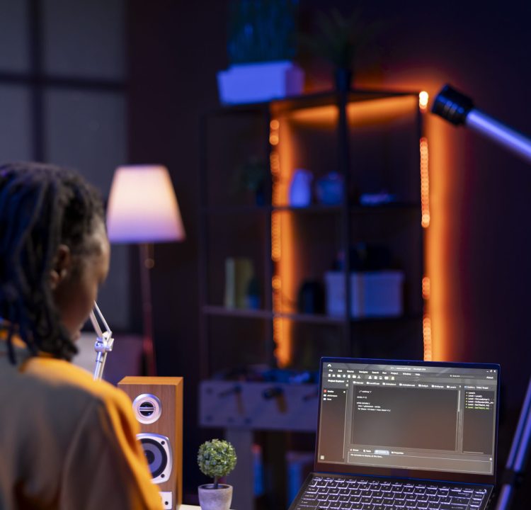 Computer scientist writes code on laptop screen while in apartment office using Java programming languages. African american teenager remotely working on fixing database errors