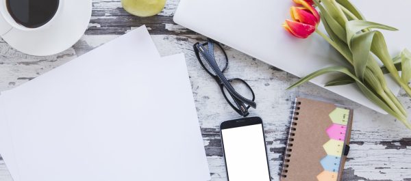 papeis-e-xicara-de-cafe-perto-de-smartphone-na-mesa-com-flores-tulipa